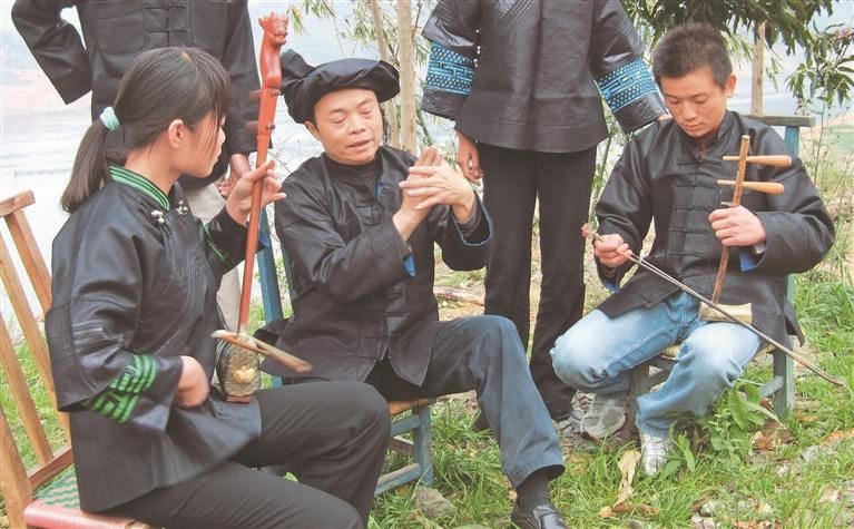 梁秀江(右)正在教授徒弟演奏
